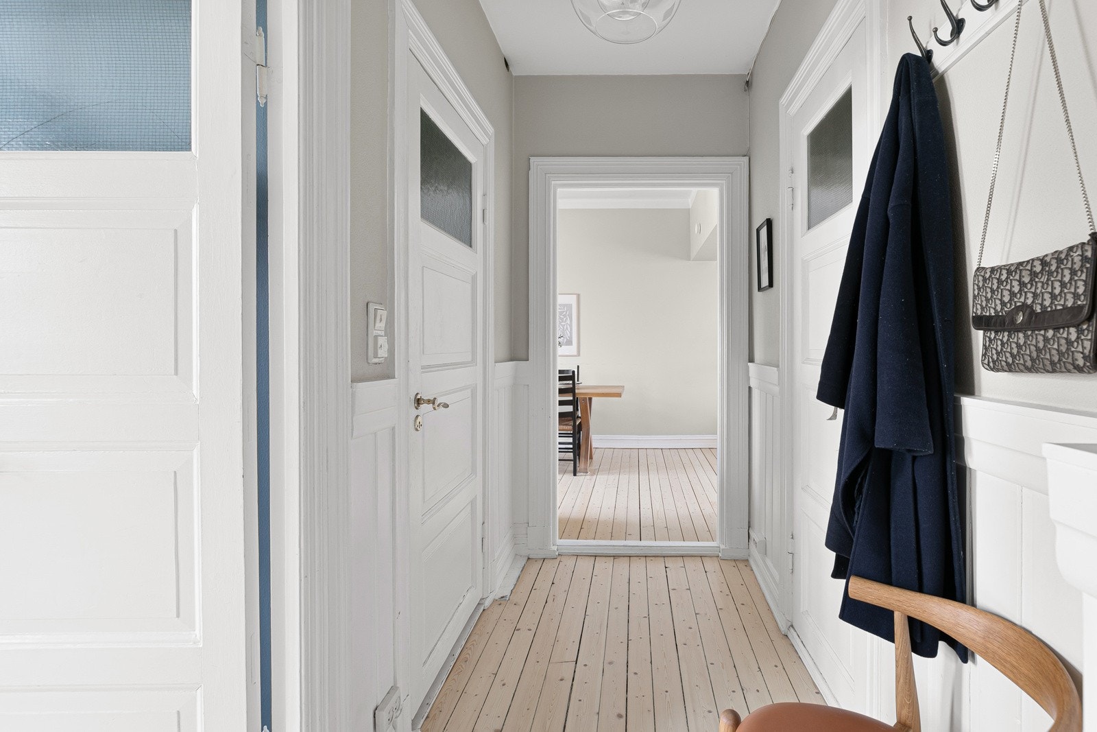 Lys og innbydende entré med detaljer som gjentar seg gjennom leiligheten - nyslipte originale tregulv, lyse vegger og generøs himlingshøyde. Galleribilde