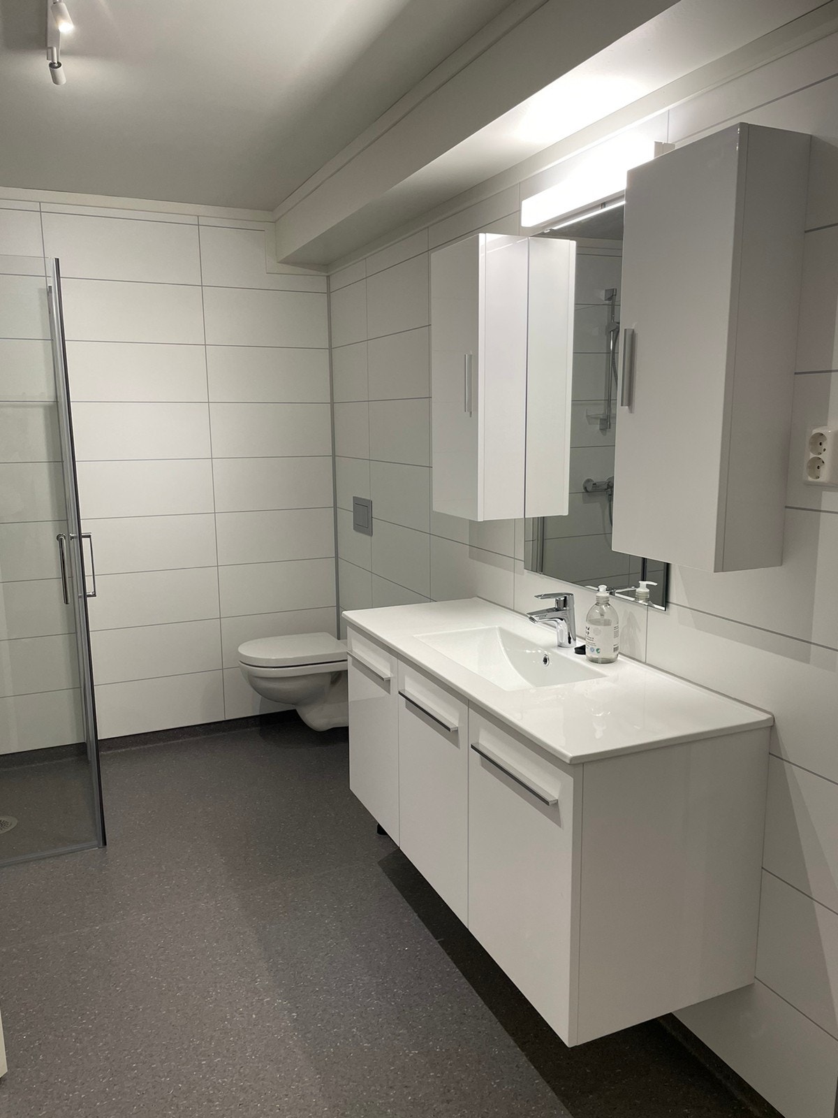 Stort bad med dusj, toalett, hyller og skap, samt vaskemaskin. Galleribilde