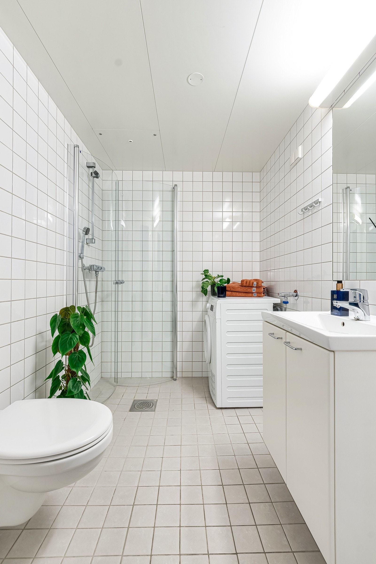 Badet er innredet med servantskap, speil, vegghengt toalett og dusjhjørne med svingbare dusjvegger. Galleribilde