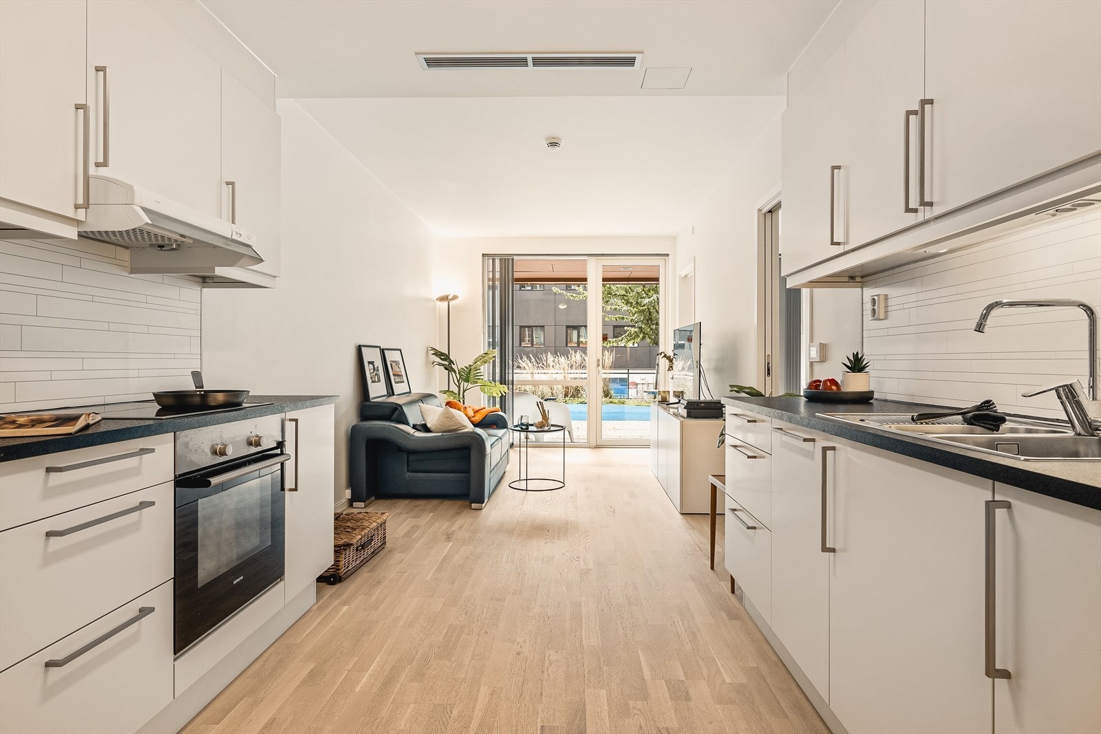 Boligens oppholdsrom, bestående av en stor åpen stue-/kjøkkenløsning. Galleribilde