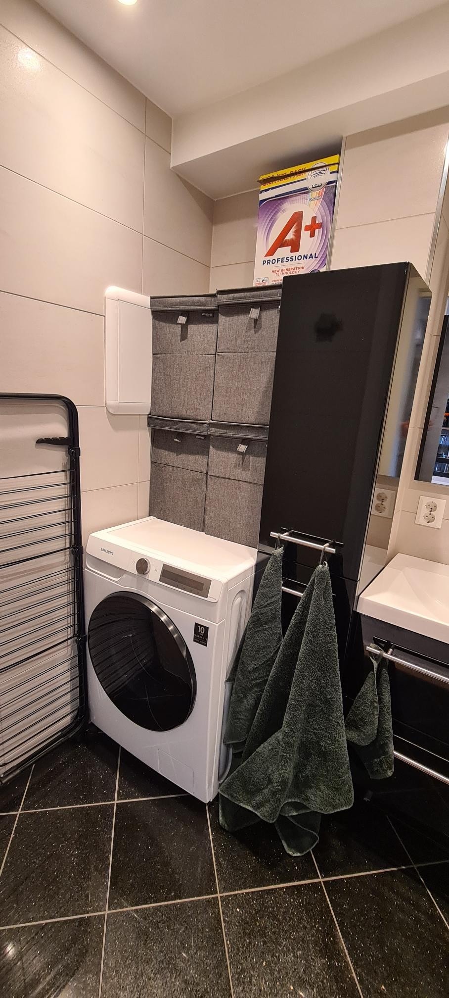 Vaske -og tørkemaskin på badet, skittentøyskurver over og tørkestativ som får plass foran maskinen. Galleribilde