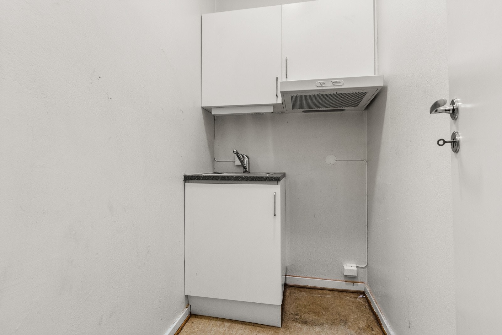 Enkelt kjøkken med hvit plan innredning med laminat benkeplate. Kjøkkenventilator med kullfilter. Galleribilde