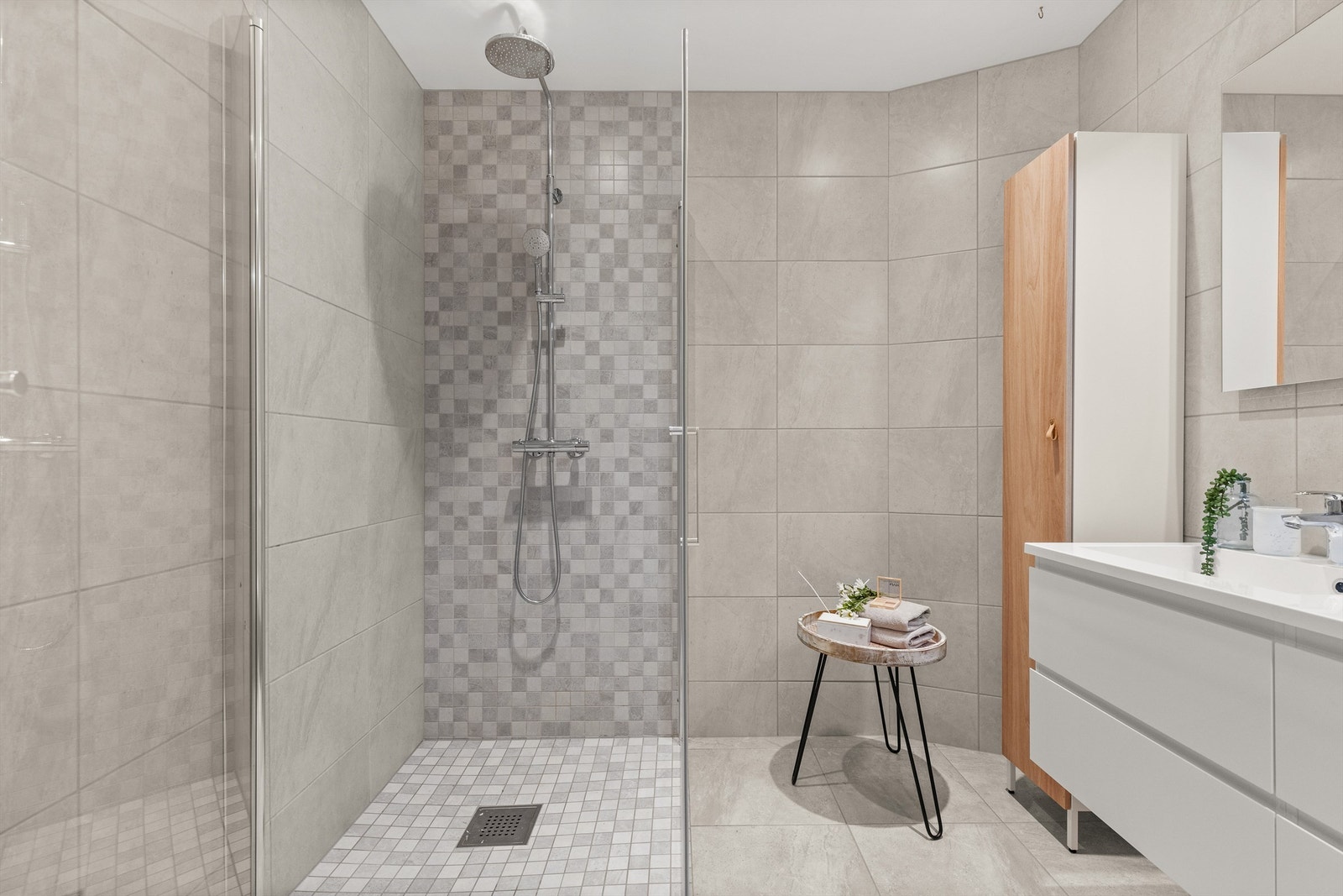 Badet har dusjhjørne med foldedører av glass og regnfallsdusj Galleribilde