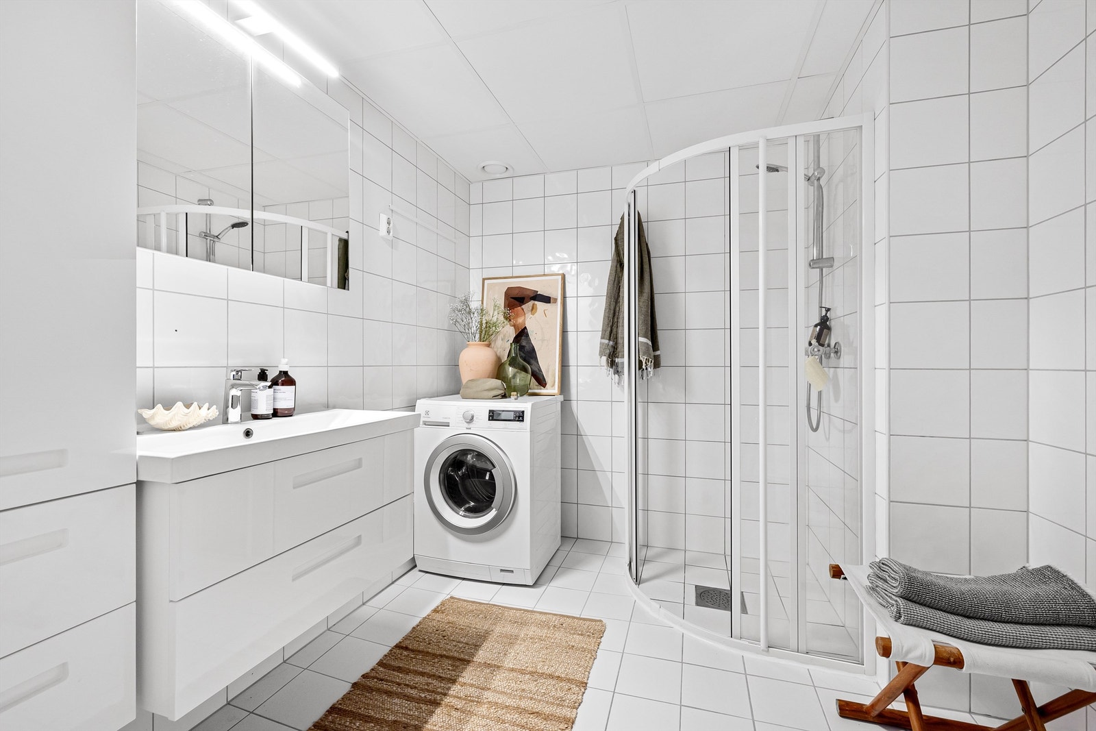 Lyst og flislagt bad med gulvvarme med plass og opplegg for vaskemaskin og tørketrommel Galleribilde