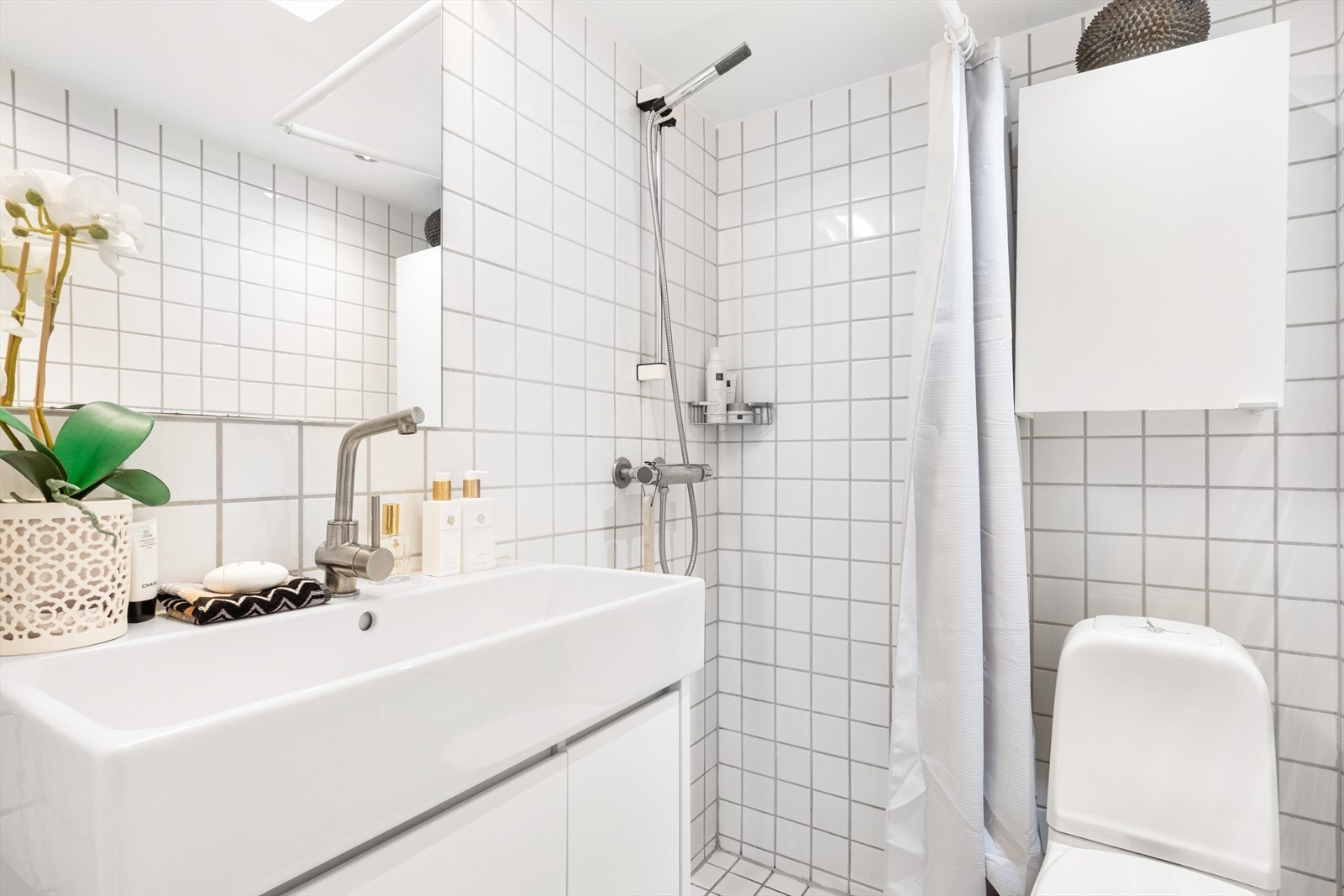 Servant med skap under, dusjhjørne, toalett og skap for ytterlige oppbevaring over toalettet. Galleribilde