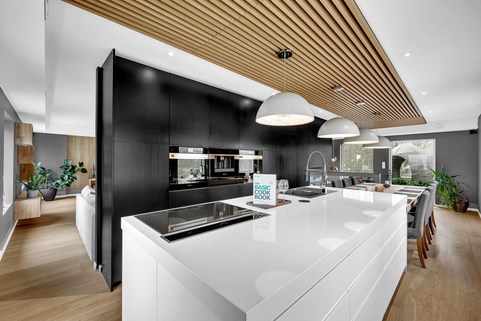 Kjøkkenøya har hvite fronter og hvit, blank laminatbenkeplate med kum i kompositt. Galleribilde
