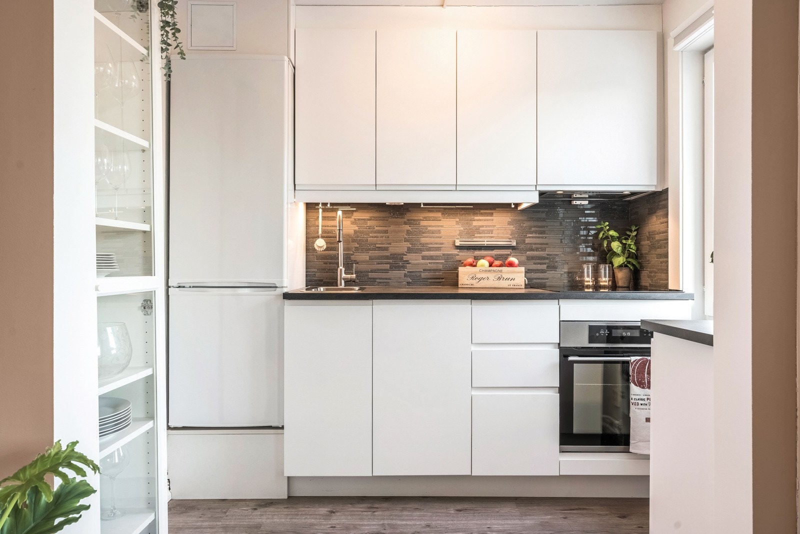 Kjøkkenet er utstyrt med hvit glatt kjøkkeninnredning fra 2017, laminat benkeplate, fliser over benk, utslagsvask med ett-greps blandebatteri og kjøkkenventilator. Galleribilde