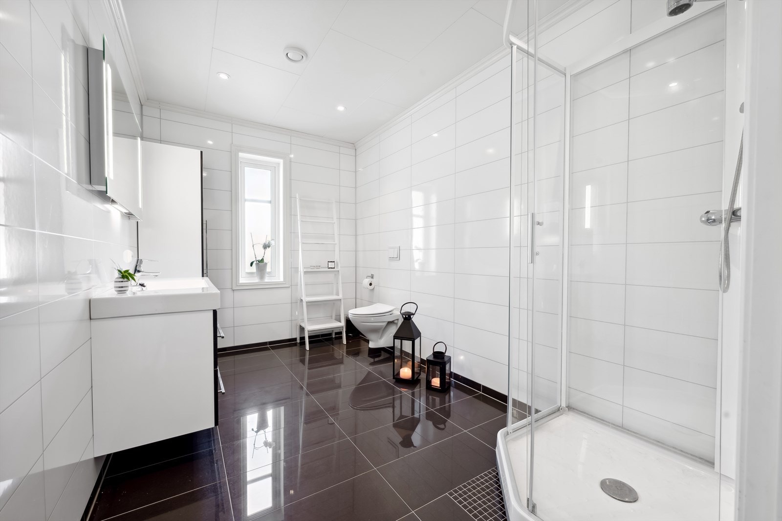 Badet i 1.etasje har sanitærutstyr bestående av dusjkabinett, heldekkende servant, speil og veggmontert toalett. Galleribilde