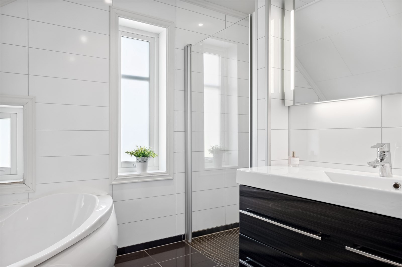 Baderommene har innredning av samme kvalitet med glatte fronter og oppbevaring i skuffeseksjon. Galleribilde