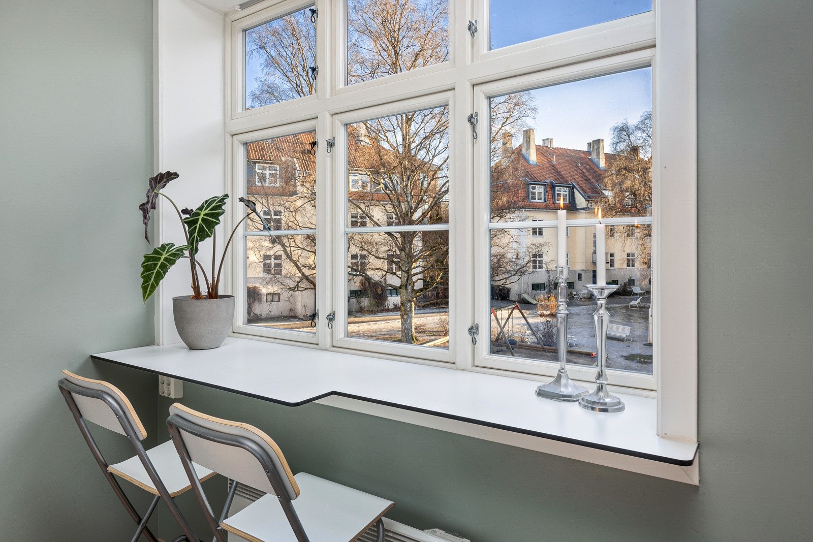 Liten spisplass ved kjøkkenvindu, med utsyn mot gårdsrom Galleribilde