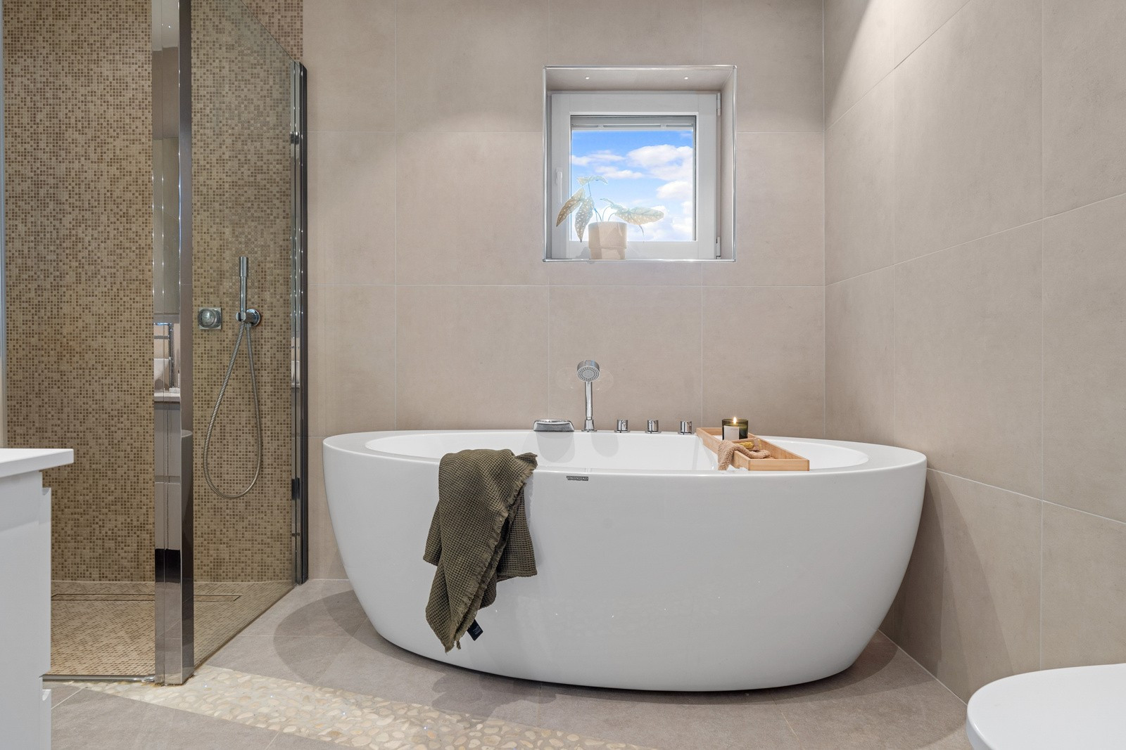 Badet er komplett flislagt med store fliser i en tidstriktig farge, samt mosaikkfliser i dusjen.