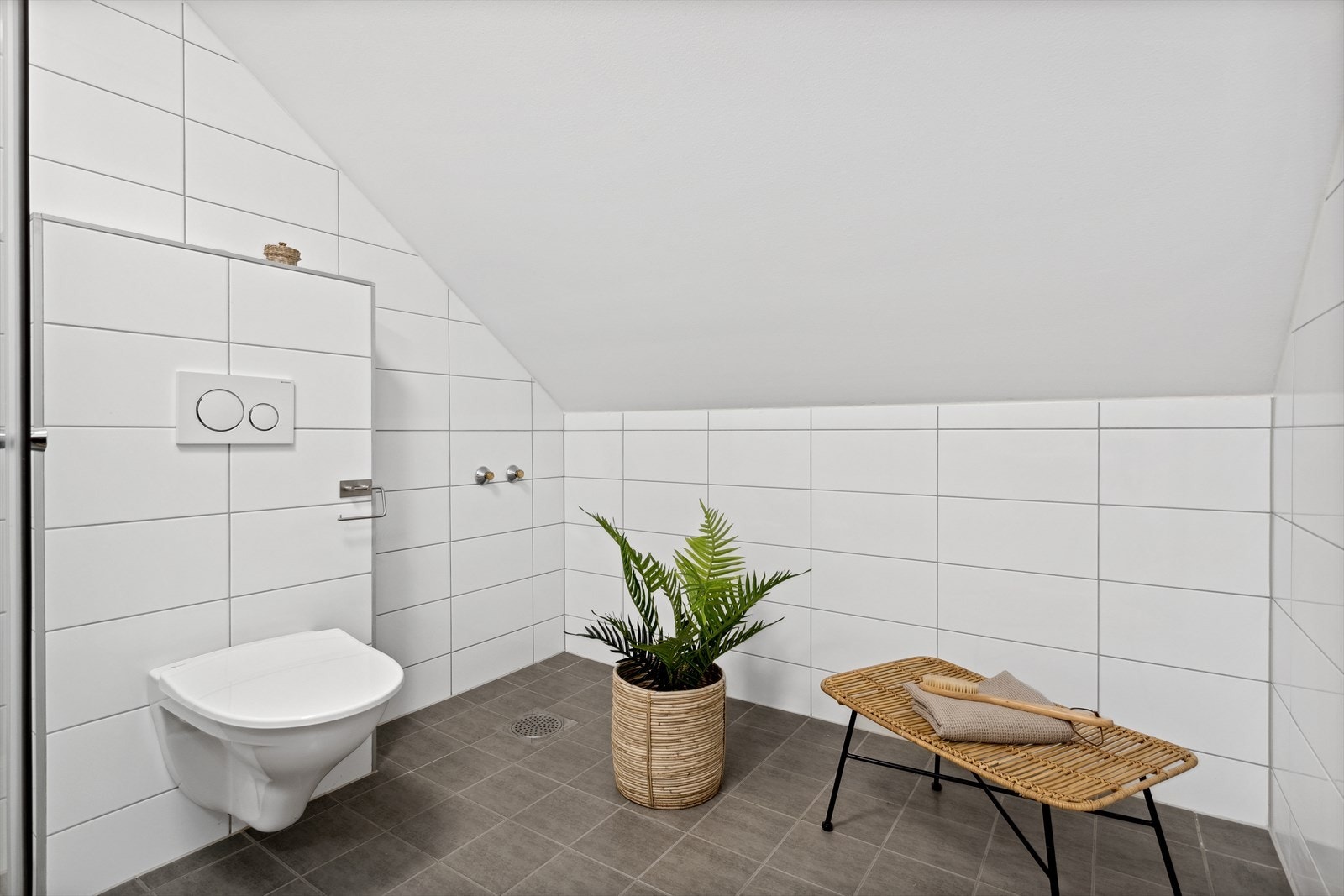Badet inneholder dusjhjørne med vendbare dusjdører, servant, speil med skap, vegghengt toalett og opplegg til badekar. Galleribilde