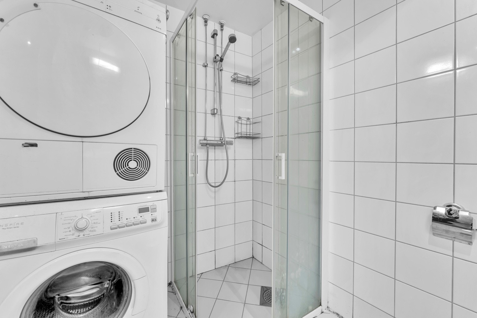Badet har opplegg for vaskemaskin og et dusjhjørne med skyvedører av glass. Galleribilde