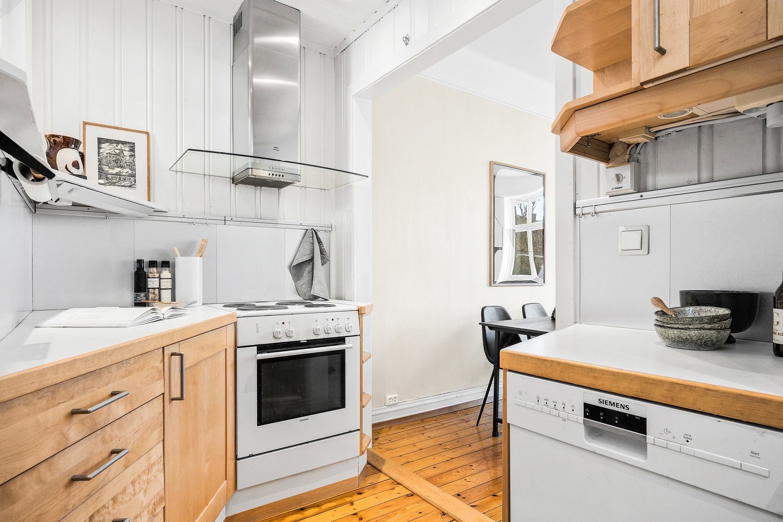 Kjøkkenløsning med frittstående hvitevarer, heltre benkeplater og glatte fronter som har blitt oppgradert i senere tid. Galleribilde