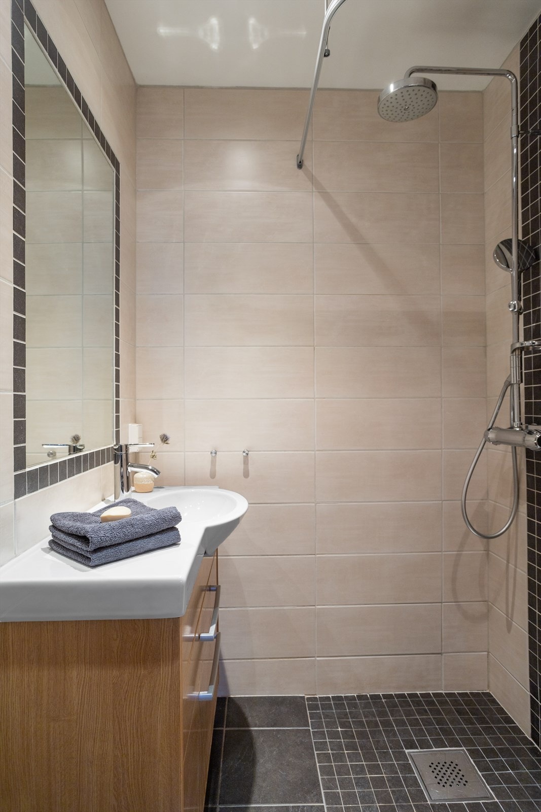 Baderommet er utstyrt med vegghengt klosett, dusjhjørne med dusjforheng og heldekkende servant med tilhørende underskap med finér fronter. Galleribilde