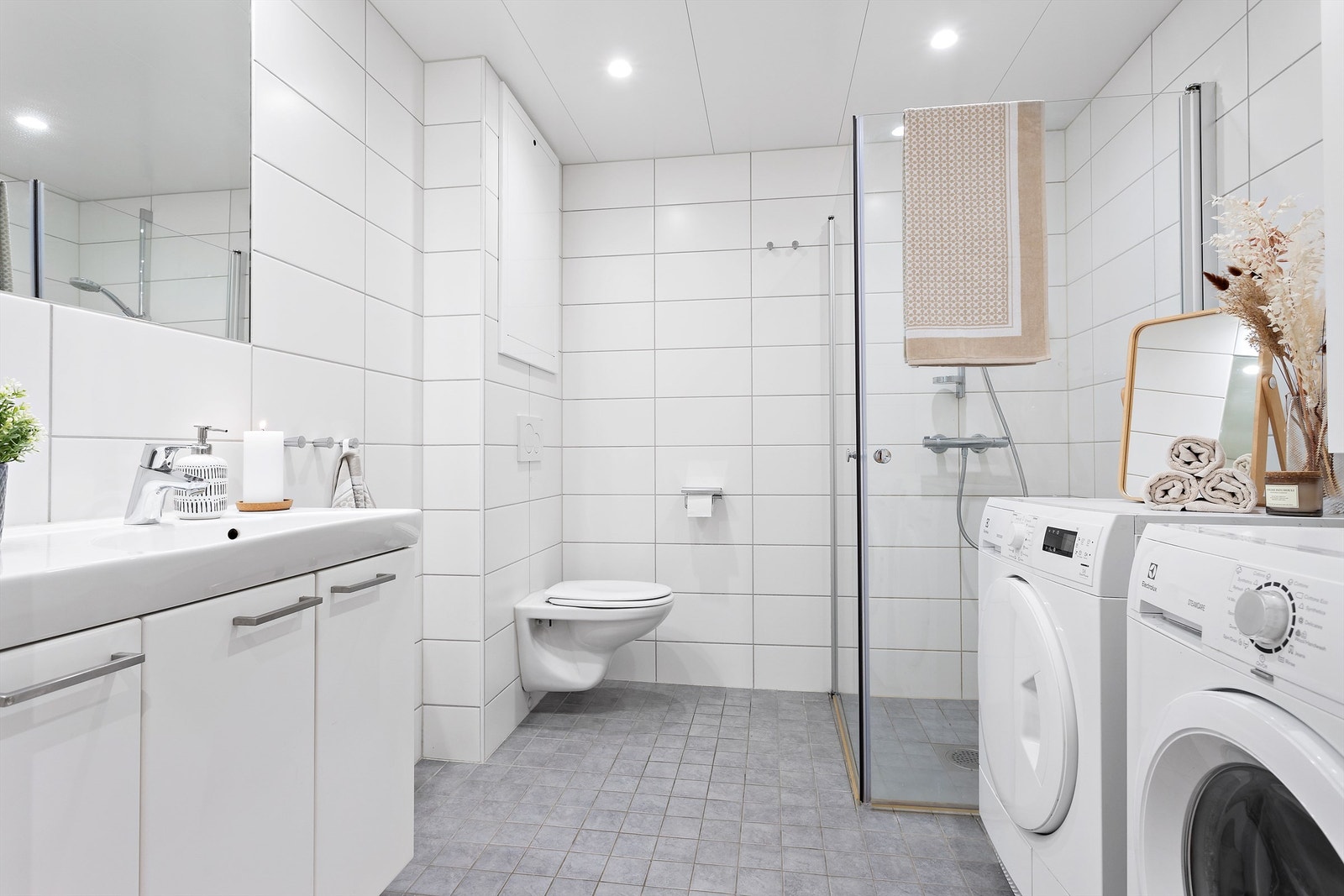 Badet på 5,5 kvm har en godt utnyttet planløsning med plass til både vaskemaskin, tørketrommel og ekstra oppbevaring i tillegg til baderomsinnredningen Galleribilde
