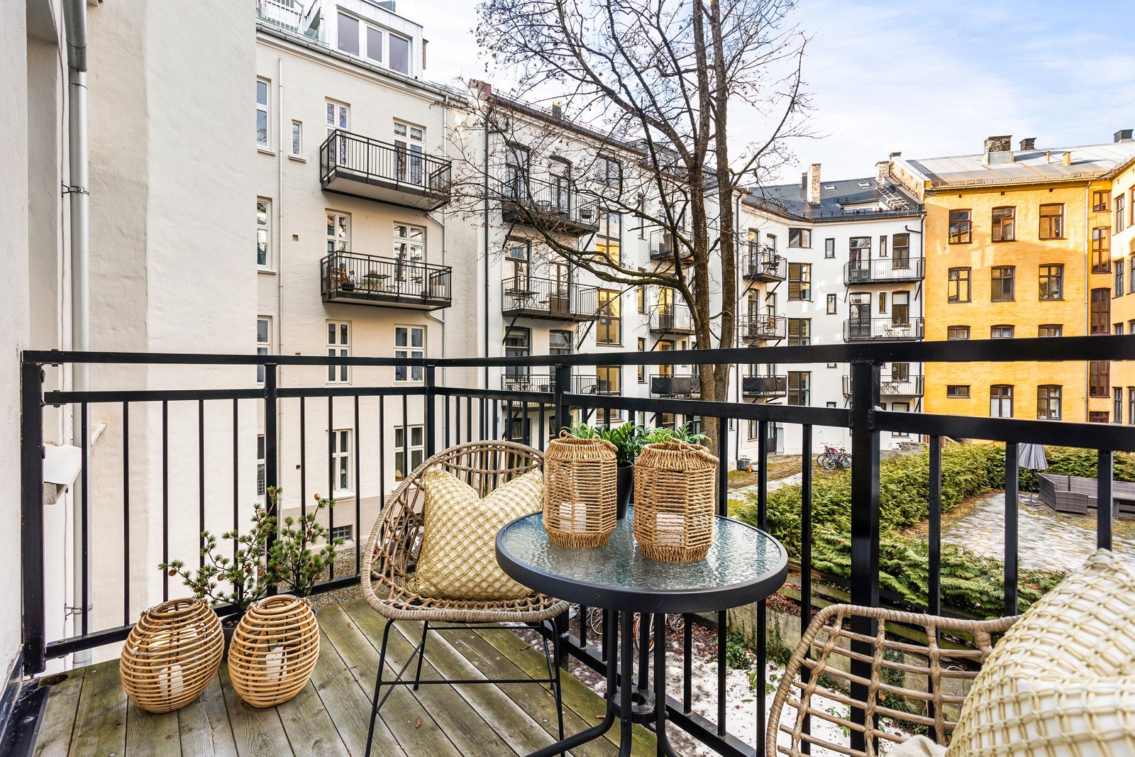 Balkongen vender ut mot en hyggelig bakgård, har rekkverk i aluminium og terrassebord i tre Galleribilde