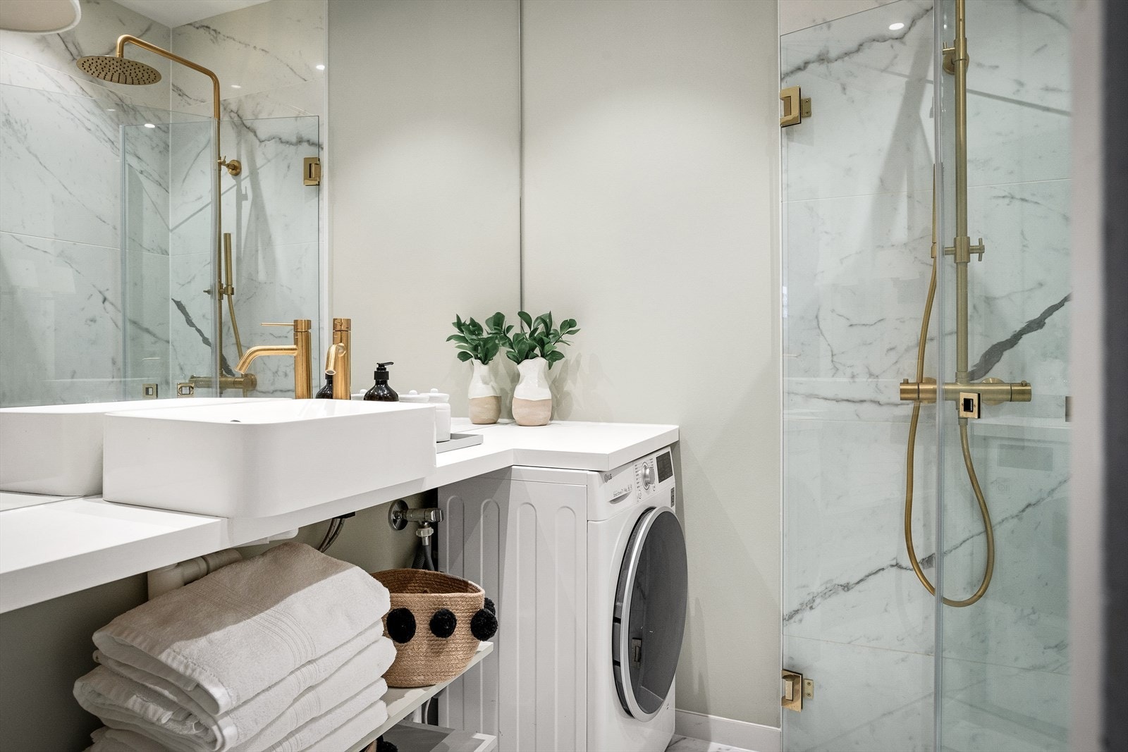 Badet er utstyrt med vegghengt toalett, dusjhjørne med innfellbare glassdører og en plassbygget servantinnredning med nisje til vaskemaskin Galleribilde