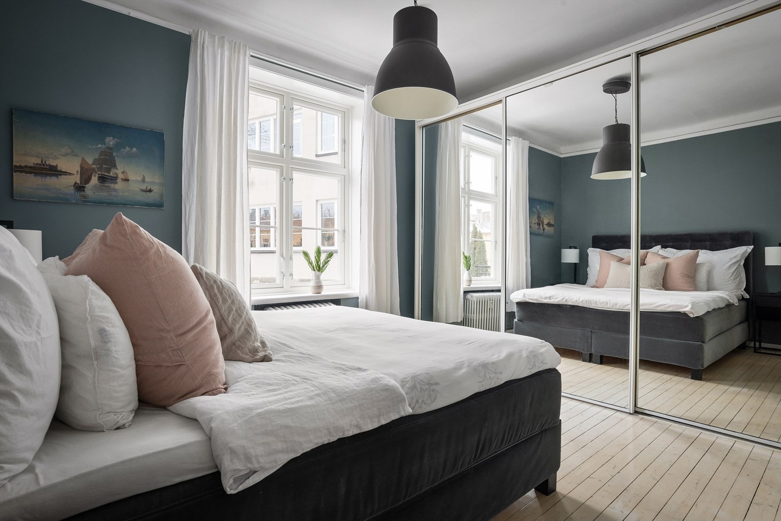 På den ene veggen finner du en stor skyvedørsgarderobe med glassdører som gir rikelig med oppbevaringsplass til klær og sko Galleribilde