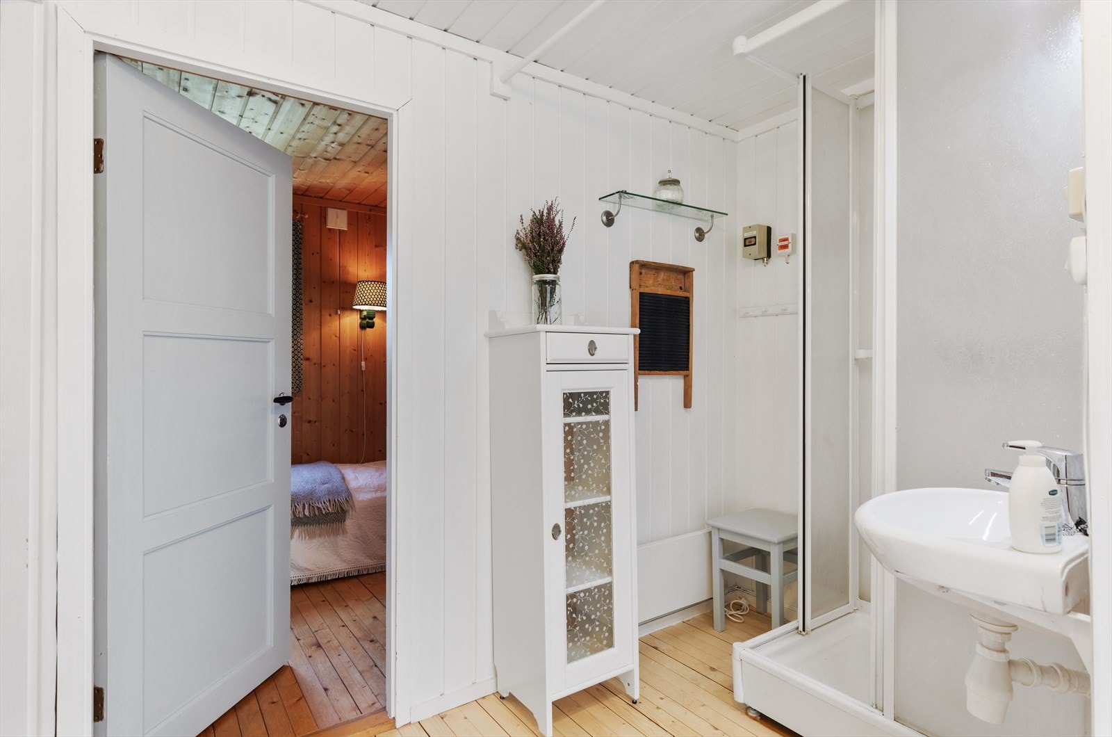 Hytta inneholder et hyttebad i gang med forheng. Her er det panel på vegger og himling, servant, speil og dusjkabinett. Galleribilde