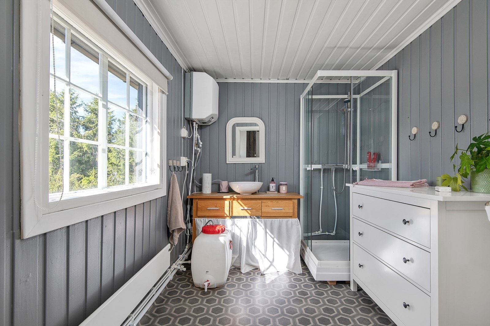 Pent og delikat baderom med hyttedusj og servant. Malt i lune fine farger. Stort vindu slipper inn godt lys i rommet. Galleribilde