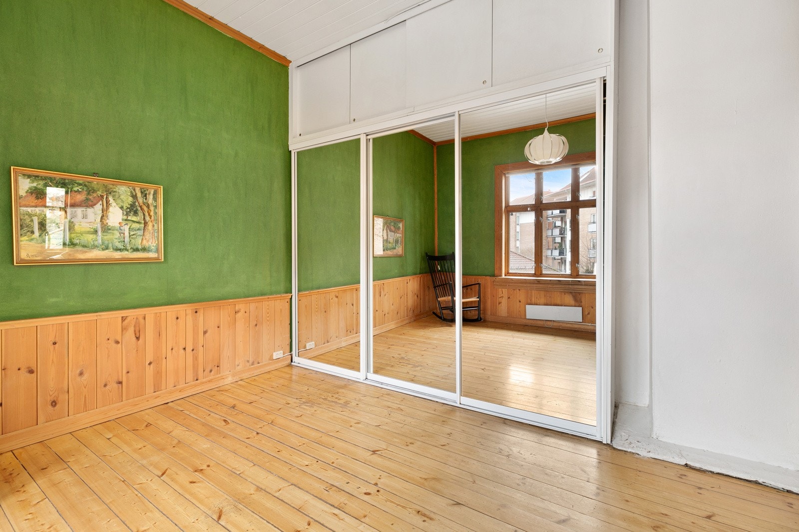 Dagslys fra et stort krysspostvindu reflekteres via en takhøy skyvedørsgarderobe. Galleribilde