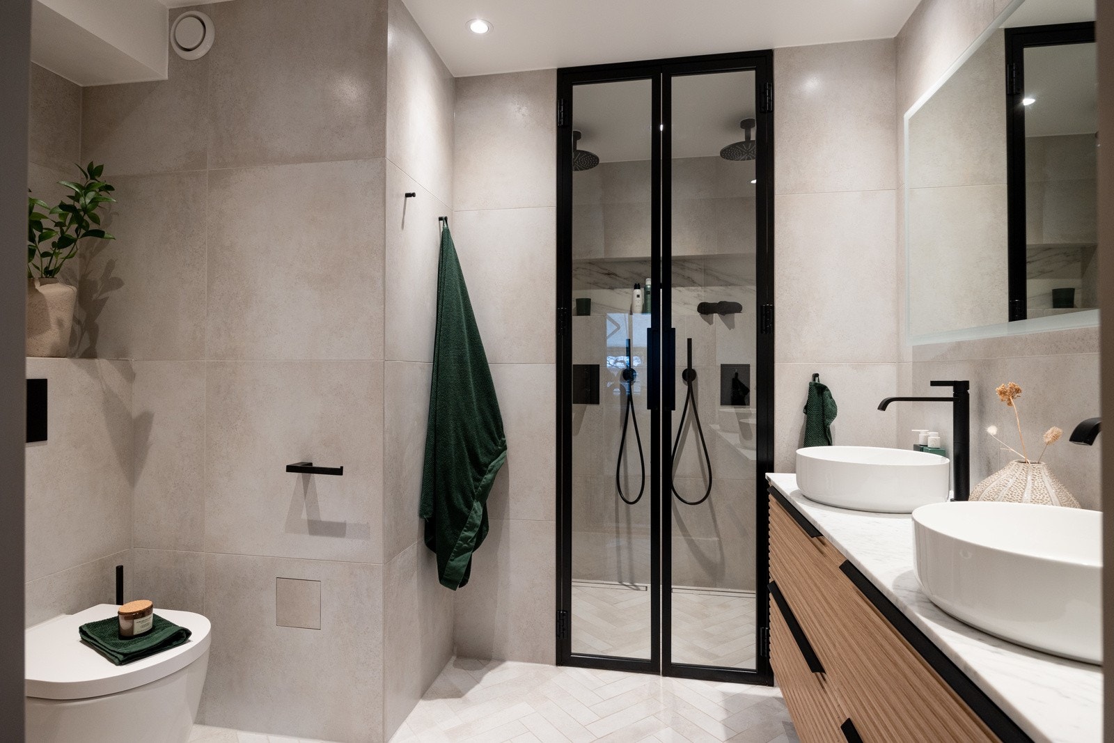 Her er det downlights i himling og innredet med vegghengt toalett, dobbelservant på vegghengt servantskap og dusjdører i glass. Galleribilde