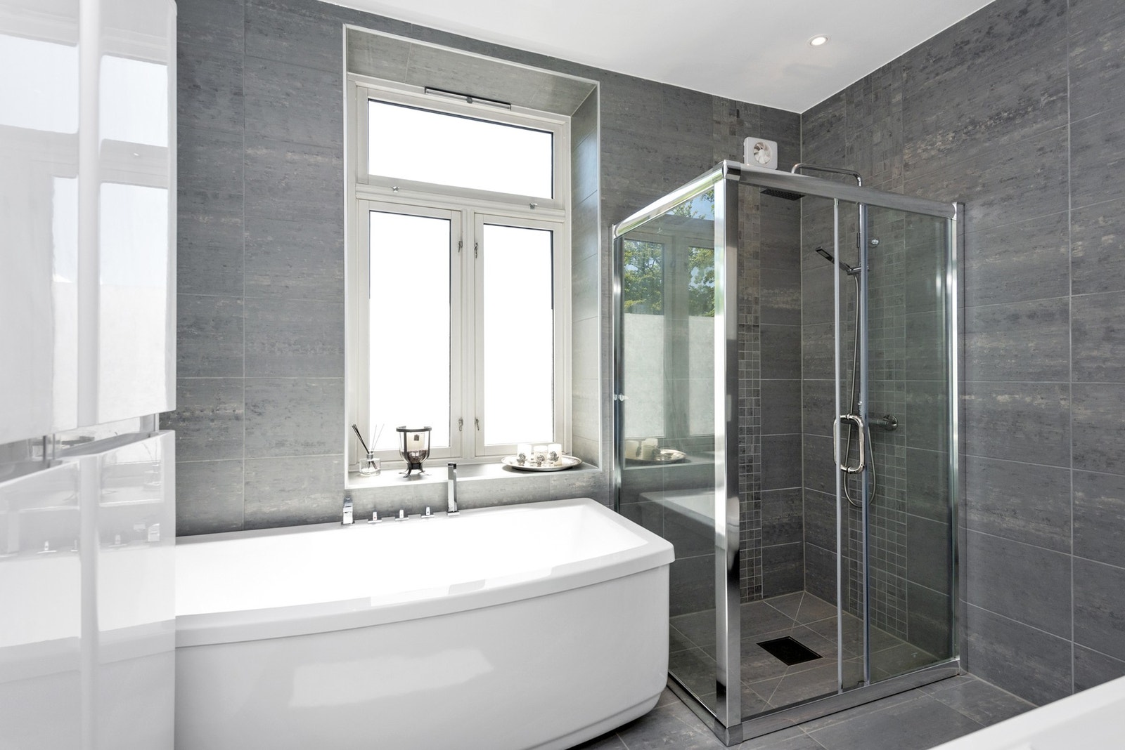 Badet er innredet med vegghengt toalett, dusjhjørne, badekar og innredning i høyglans med buede fronter. Galleribilde