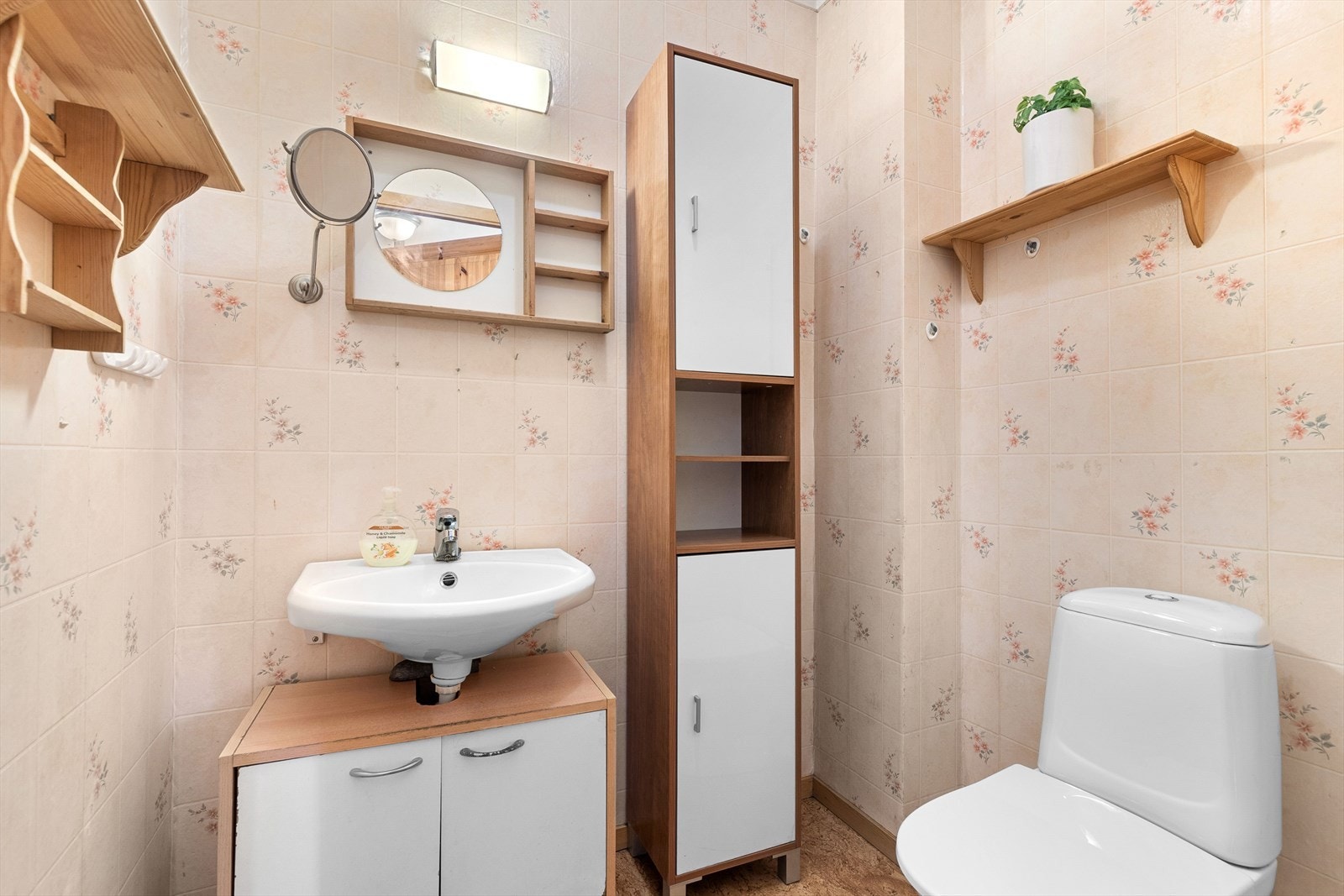 Praktisk wc rom med innredning bestående av klosett, servantinnredning og langskap. I tillegg er det hylle med speil, sminkespeil og lysarmatur Galleribilde