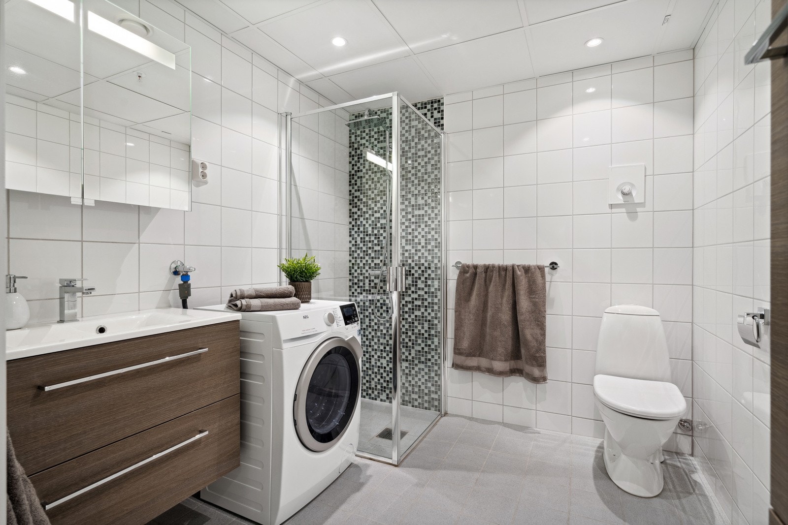 Romslig og delikat flislagt bad på hele 5 kvm med moderne innredning og opplegg for vaskemaskin Galleribilde