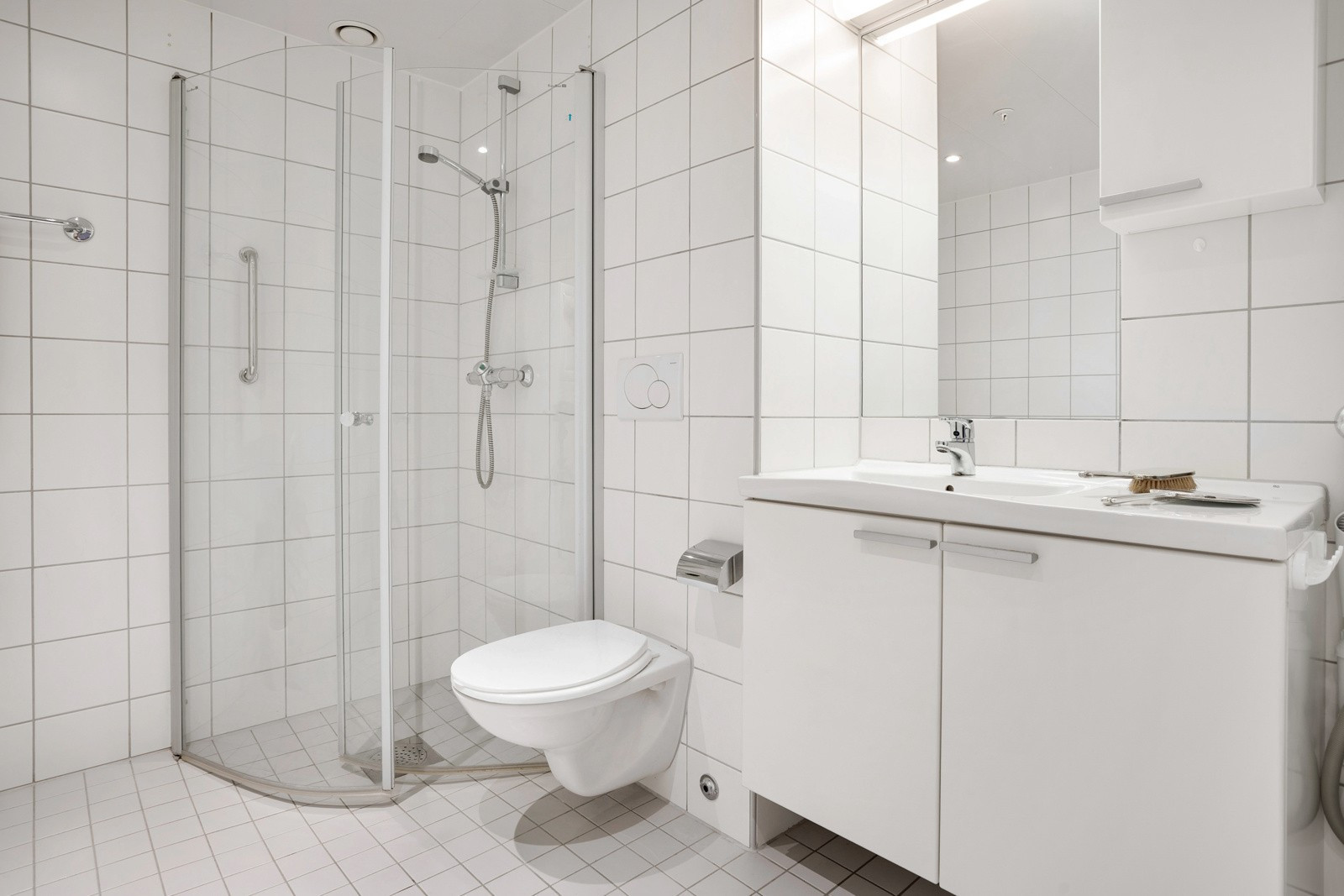 Badet er innredet med dusjhjørne, toalett og servant.