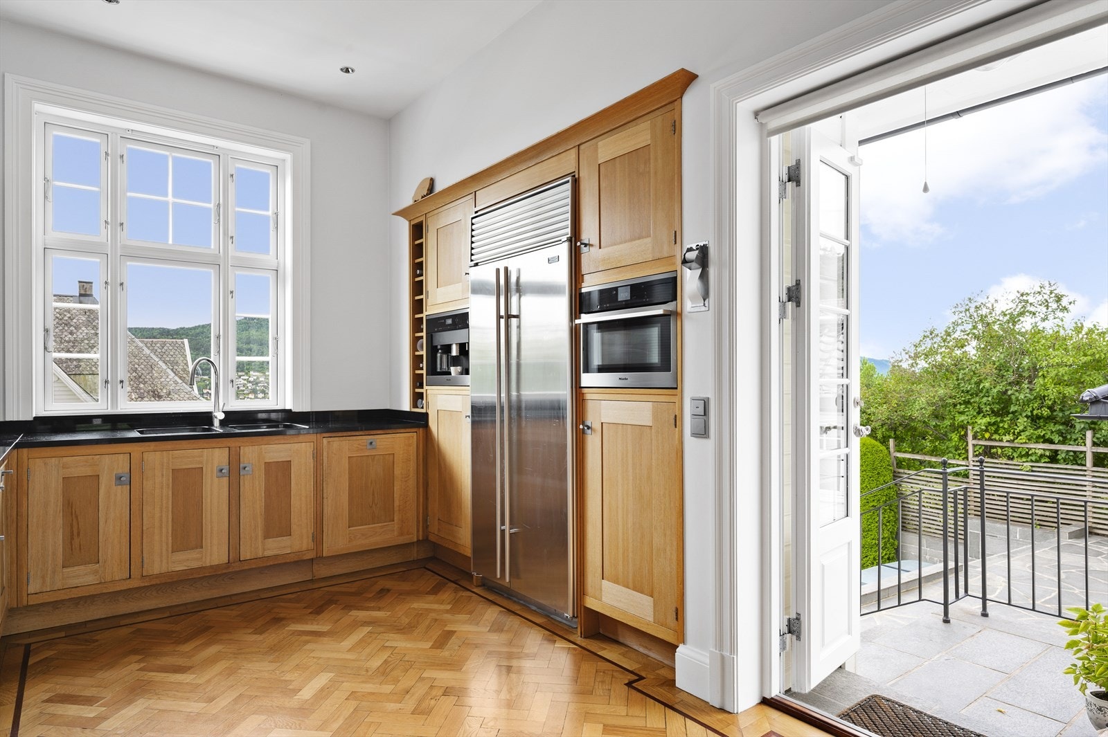 Doble dører fra kjøkken ut til hellebelagt, oppvarmet skiferbelagt uteområde, med tilgang til treningsrom som ligger på garasjens bakside. Galleribilde