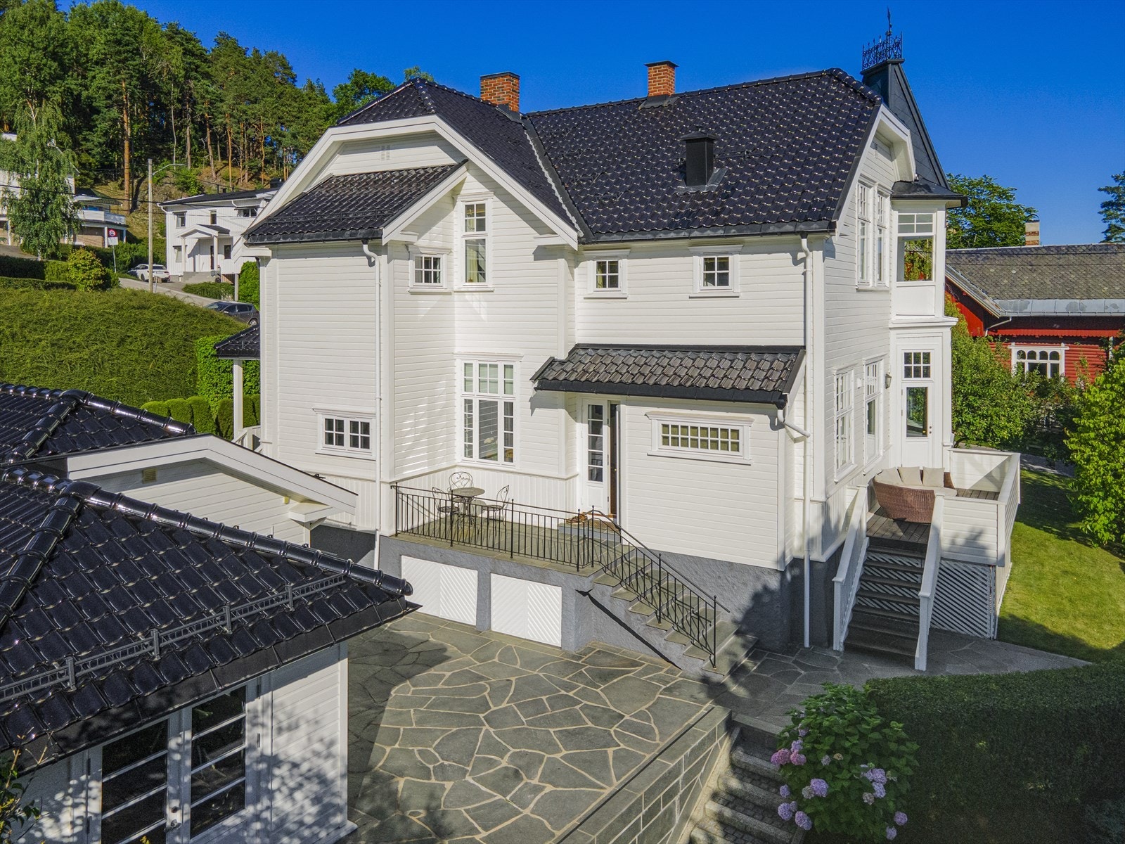 Fasade fra vest- Garasje med Treningsrom. Oppvarmet skiferplatting og steinbelagt trapp ned til Jacuzzi og vestsiden av hagen. Galleribilde