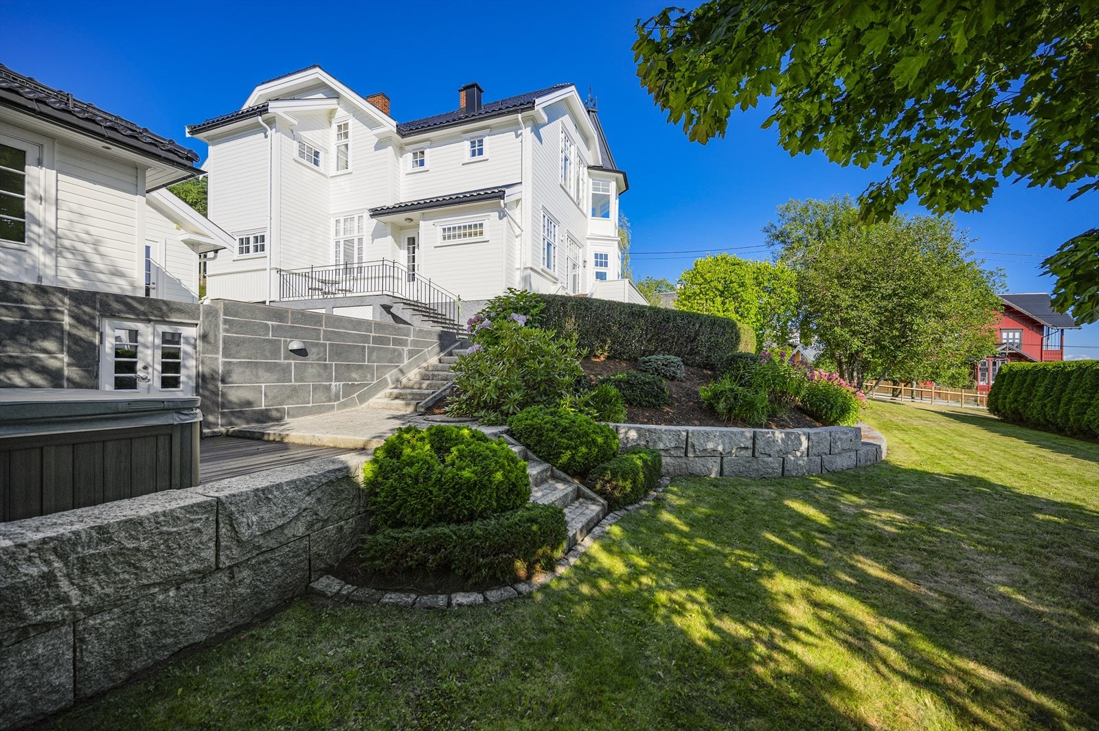 Fasade og nedre del av hagen med Jacuzzi og flott gressplen. Galleribilde