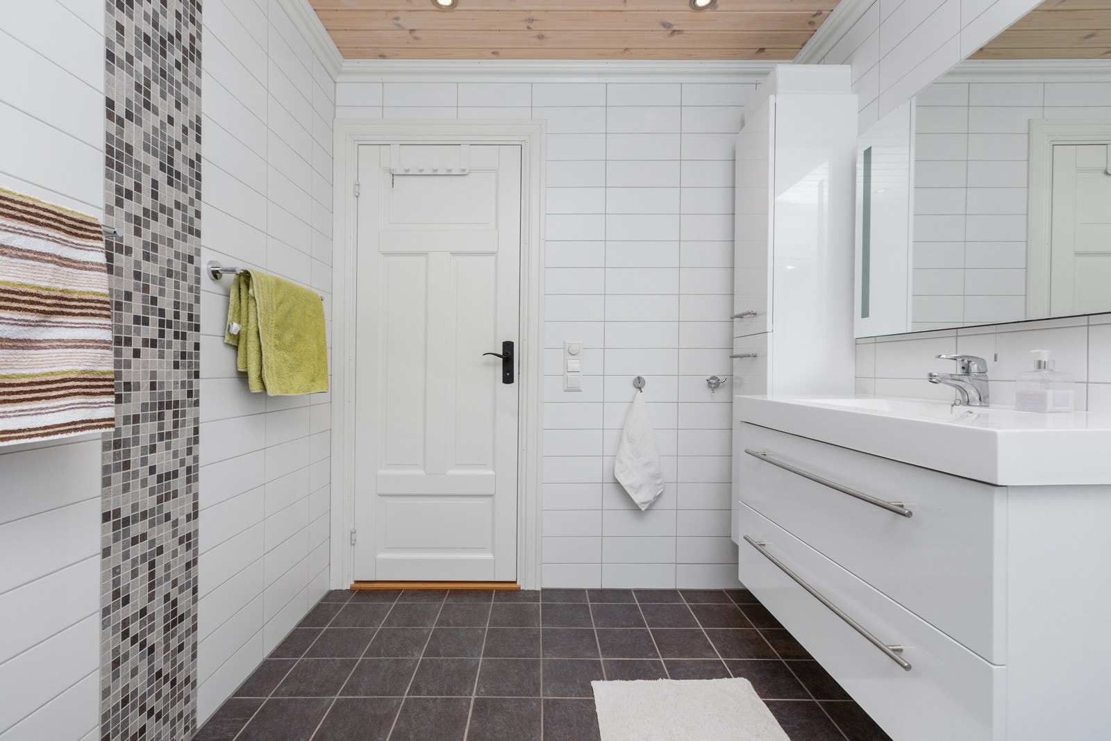 Badene er innredet med mørke fliser på gulv og lyse fliser på vegg Galleribilde