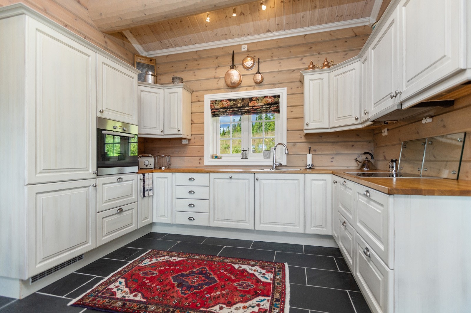 Kjøkkenet har velutstyrt innredning i heltre med lyse fronter Galleribilde