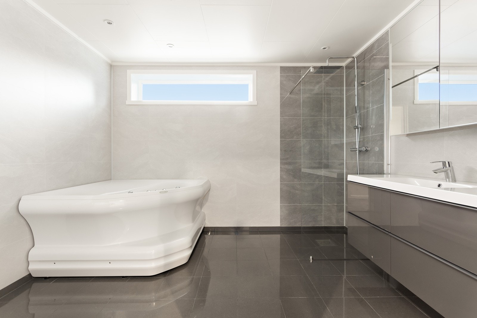 Flott, innbydende og romslig bad som virkelig innbyr til velvære. Rommet ble innredet i 2021. Fliser på gulv med gulvvarme, baderomsplater på vegg, rør i rør med fordelingsskap og spotter i himling er noe av det som er verdt å trekke frem. Galleribilde