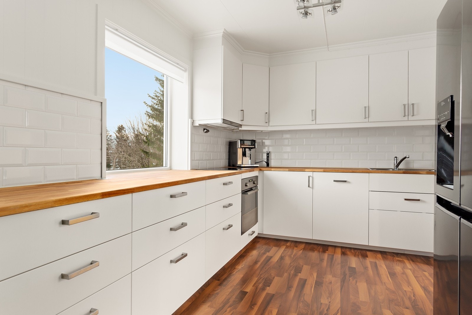 Kjøkkenet har rikelig med benk/skapplass og fliser på vegg over benkeplater. Her kan du lage mat med utsikt til naturskjønne omgivelser. Galleribilde