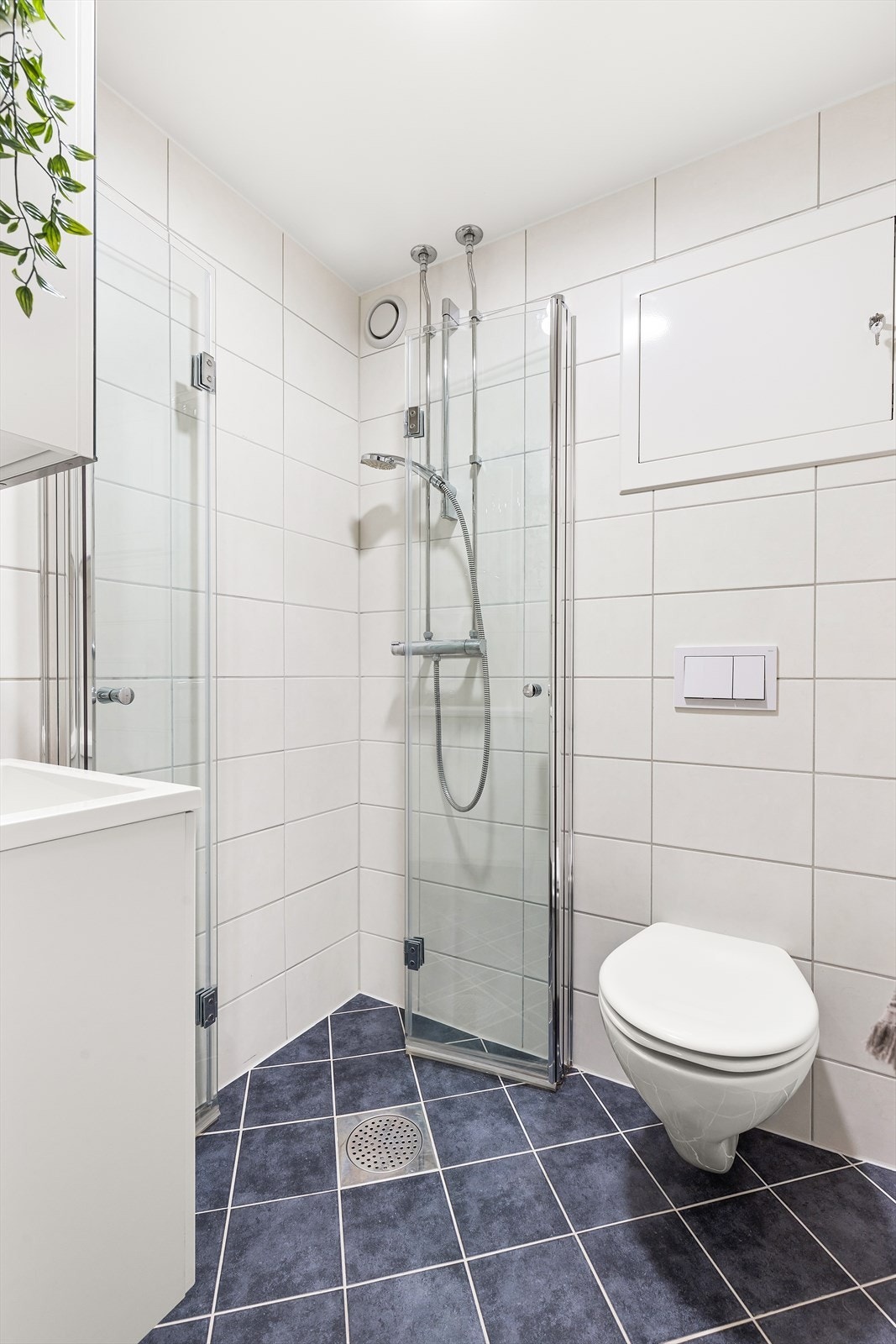 Innredningen består av servantskap, dusjhjørne med foldbare glassdører og vegghengt toalett. Galleribilde