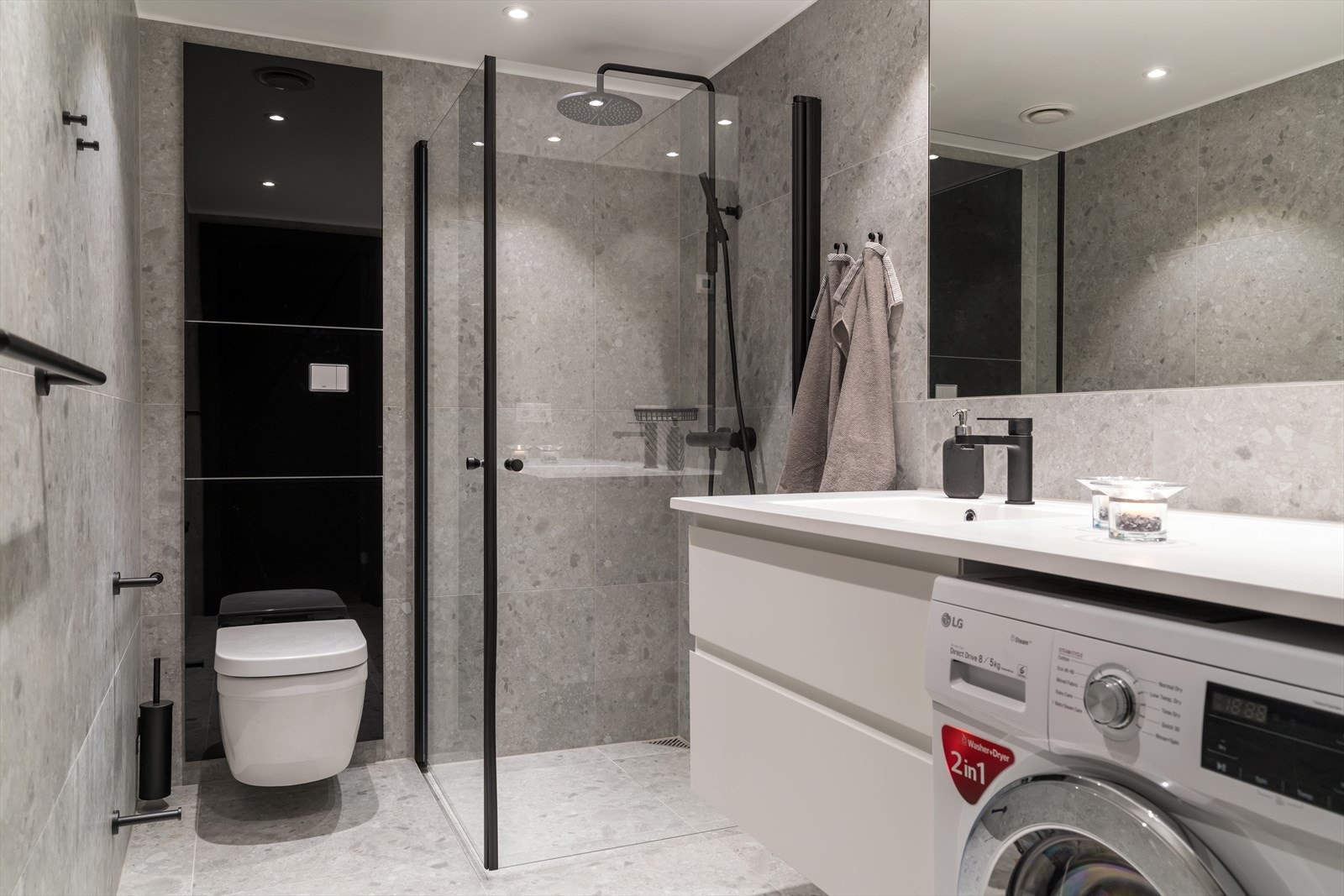 Lekkert bad med grå og sorte detaljer. Vaskemaskin medfølger. Galleribilde