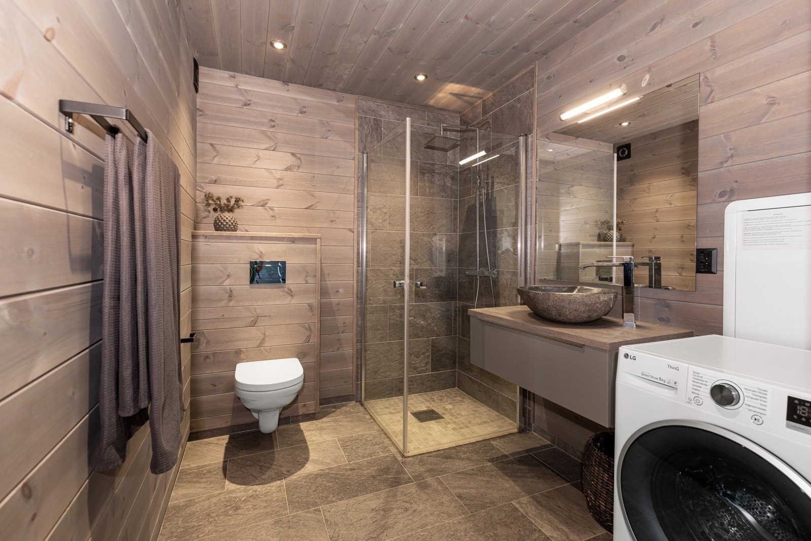 Badet har panel på veggene, flislagt gulv samt dusjhjørnet Galleribilde