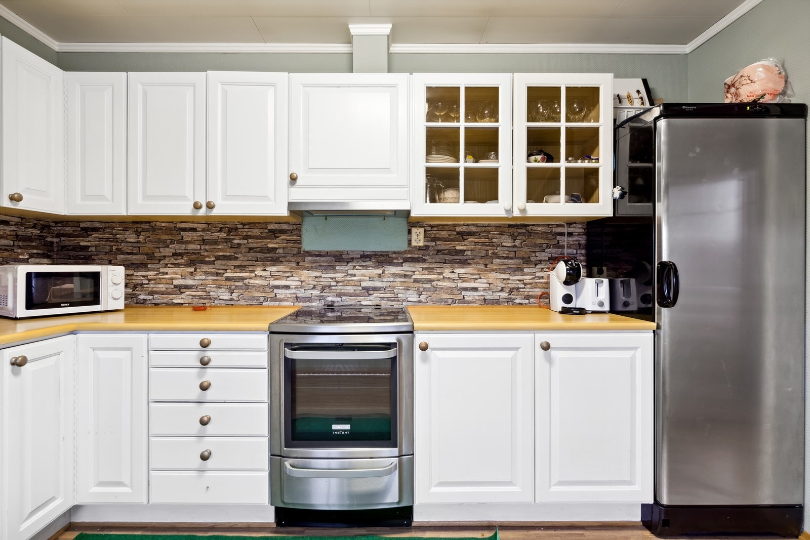 Innredningen har hvite profilerte fronter i tidløs utførelse samt enkelte vitrineskap. Her er det godt med plass for den matglade. Galleribilde