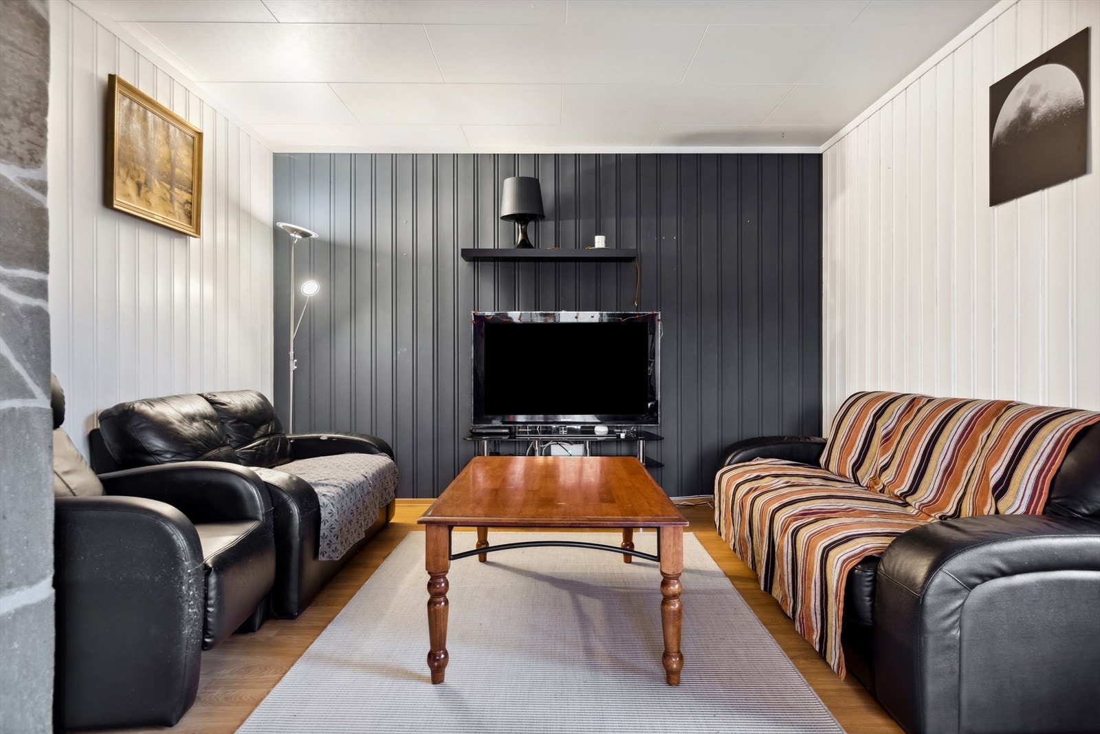 Stuen har malt panel og tapet på veggene, samt en fin steinbelagt pipe. Galleribilde