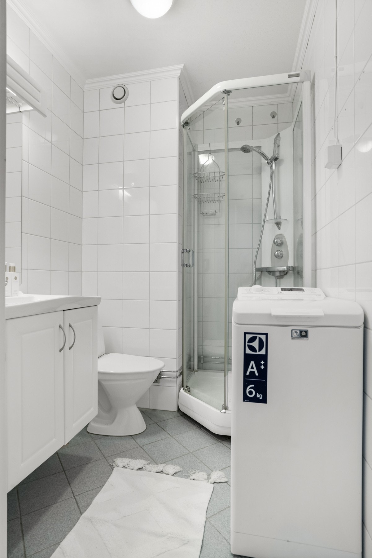 Baderom med fliser på veggene og gulvet, samt gulvvarme. Badet har baderomsinnredning, dusjkabinett, gulvklosett, uttak for vaskemaskin og mekanisk avtrekk. Galleribilde