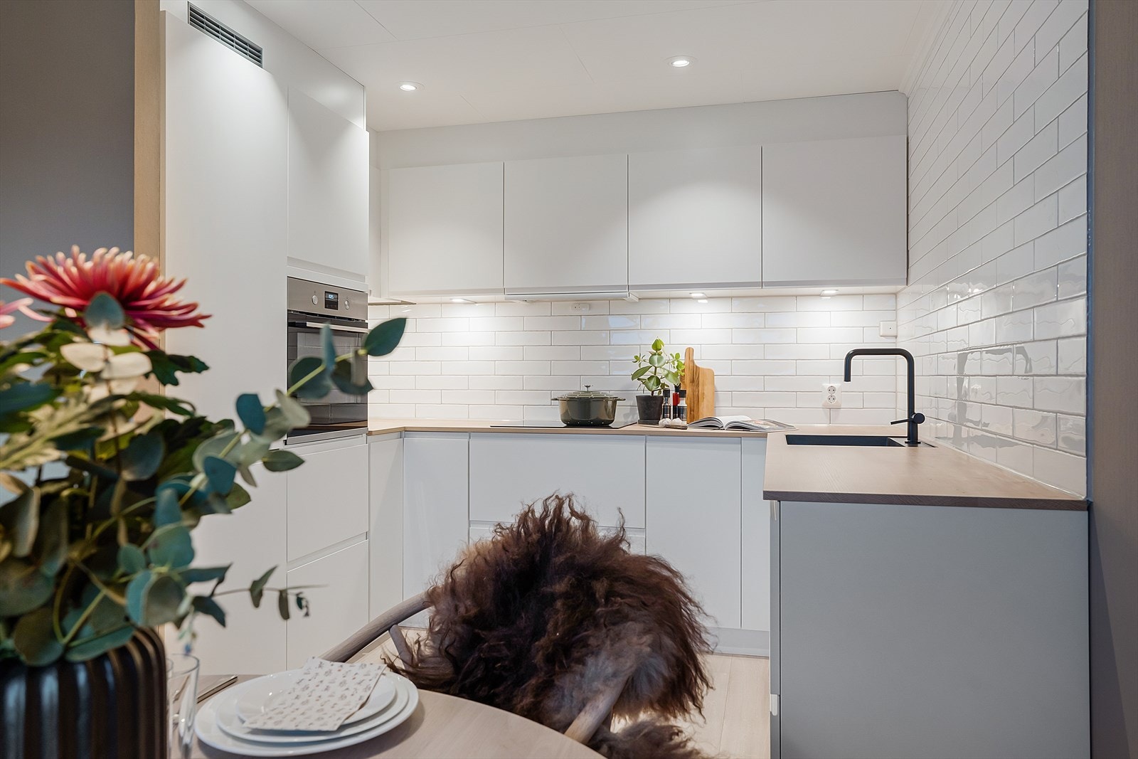 Veggene over kjøkkenbenken er fliselagt med hvite subway-fliser. Galleribilde