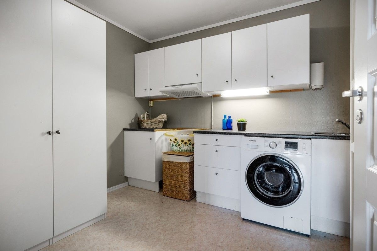 Kjøkken med vaskemaskin, komfyr, microbølgeovn og kjøleskap med fryseboks Galleribilde