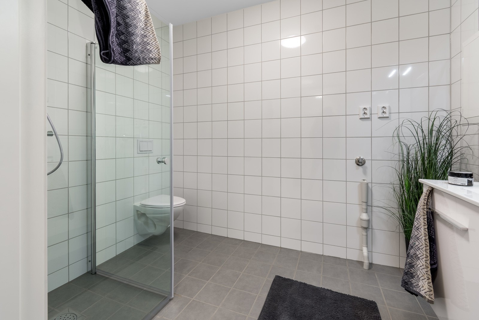 Lekkert, flislagt bad i 1. etasje med dusj, toalett, servant og opplegg for vaskemaskin. Galleribilde