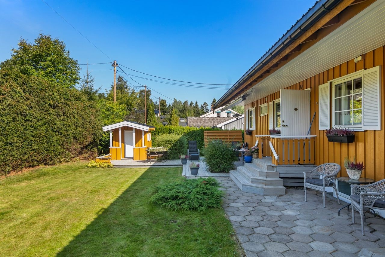 Pent opparbeidet hageområde med ettermiddagssol. Stor motorisert markise. Galleribilde