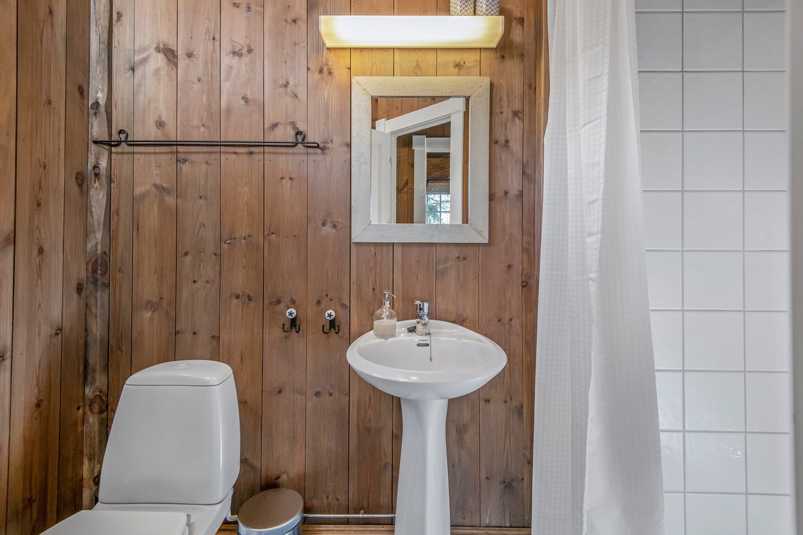 Badet i annekset har panel på vegger og fliser med gulvvarme. Galleribilde