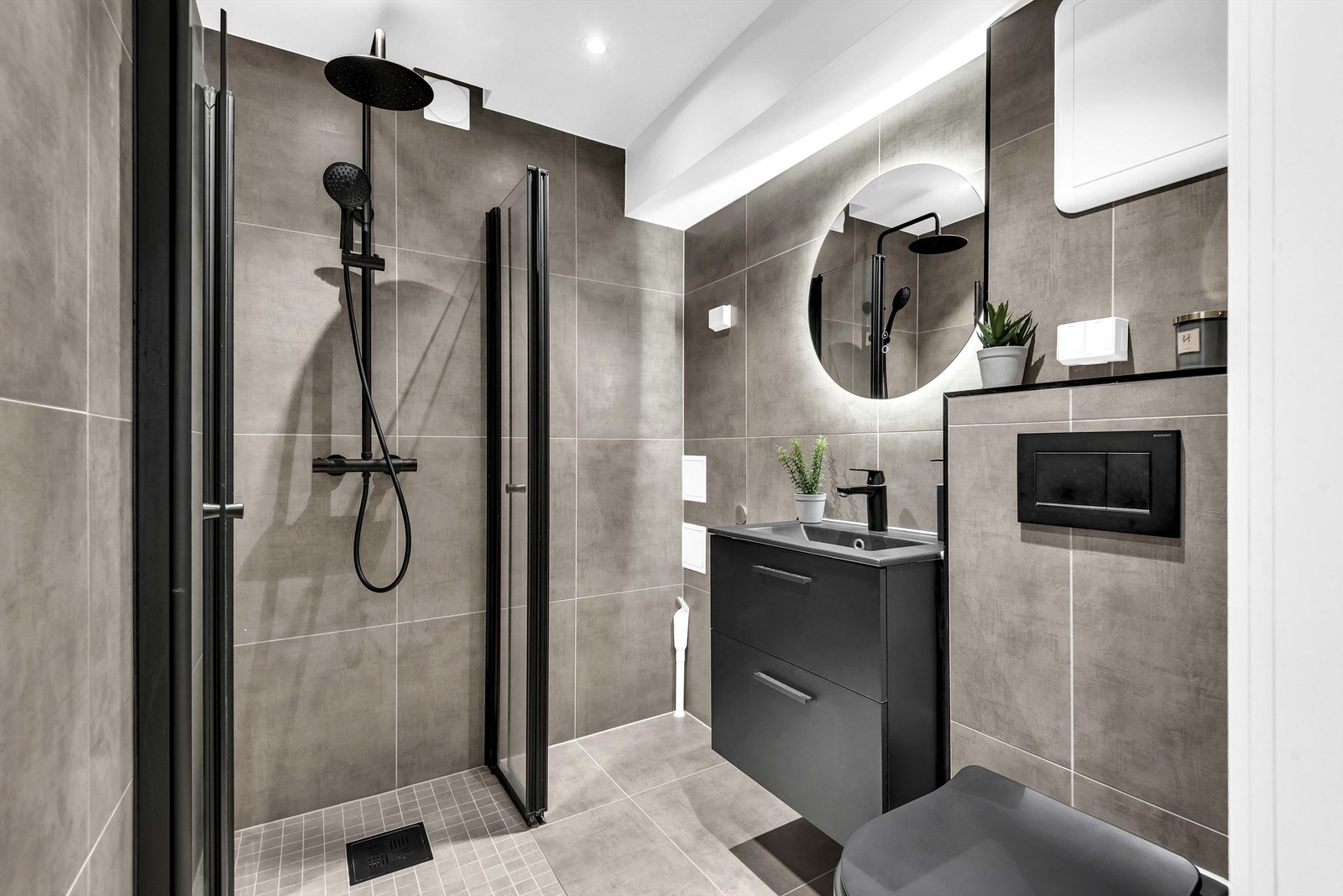 Lekkert og moderne baderom fra 2021 med downlights, regnfallsdusj, brede fliser og mørke detaljer Galleribilde